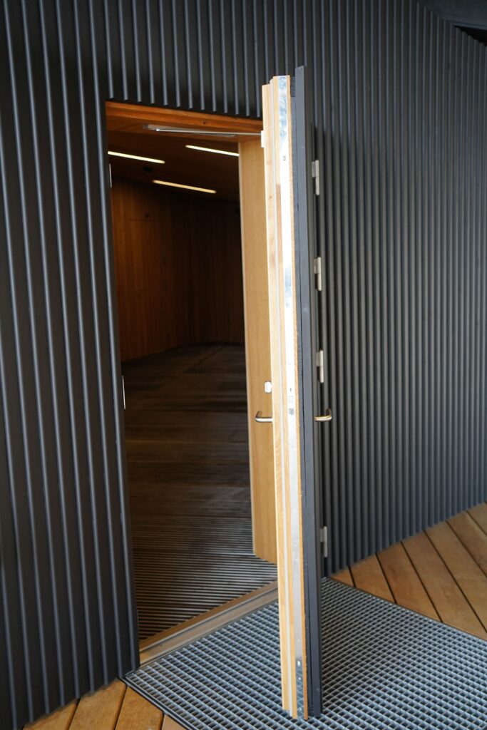 En af de usylige døre produceret af Madsen Vinduer & Døre ses her med beklædning der falder i med væggene på begge sider af dørbladet.