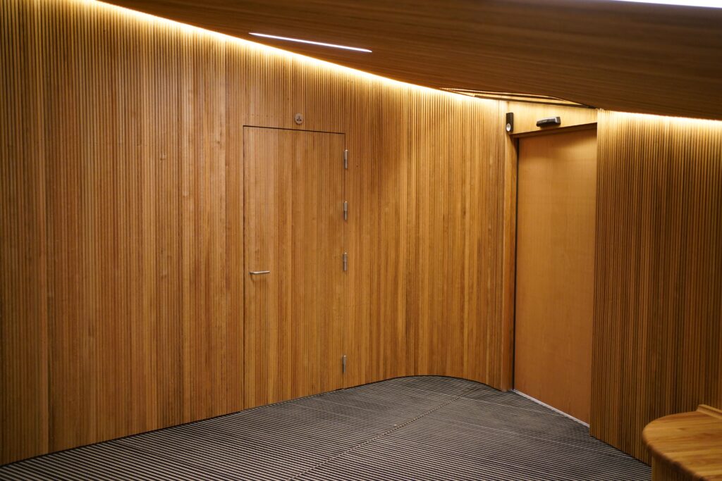 Væggen med egetræsbeklædning har en dør, der er integreret i den. Derved fremstår døren næsten usynlig.
